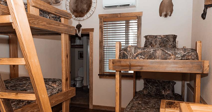 small room with 2 sets of bunk beds with camo sheets