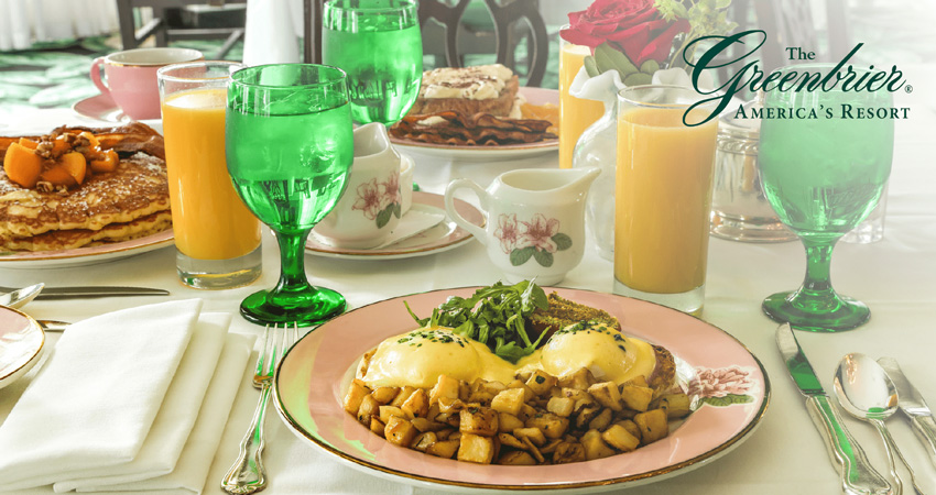 table for 3 with plates full of breakfast foods and glasses of orange juice and water