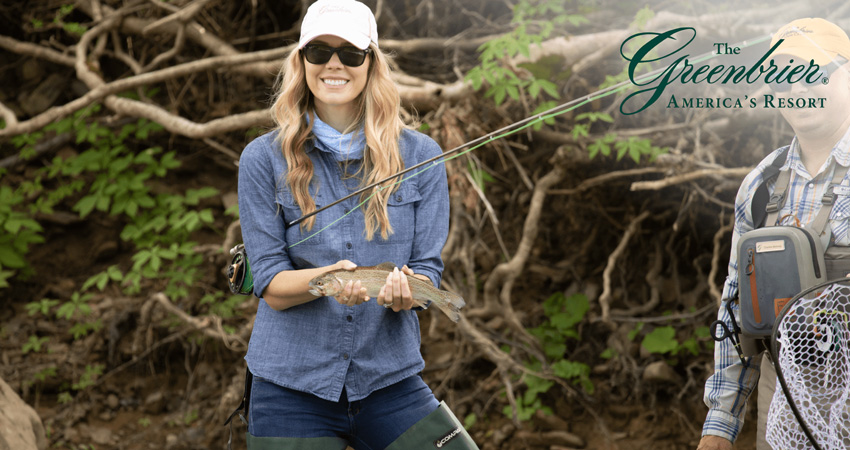 happy woman holding a fresh water fish in both hands